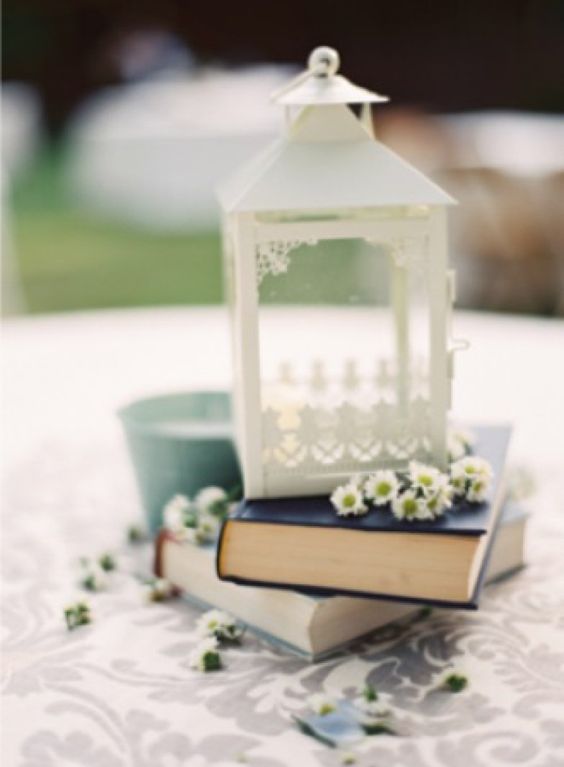 Decoração de mesa de bolo com livros, lanternas e flores, por Alessandra Faria